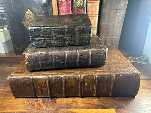 A small book stacked on top of a medium book, further stacked on top of a large book.