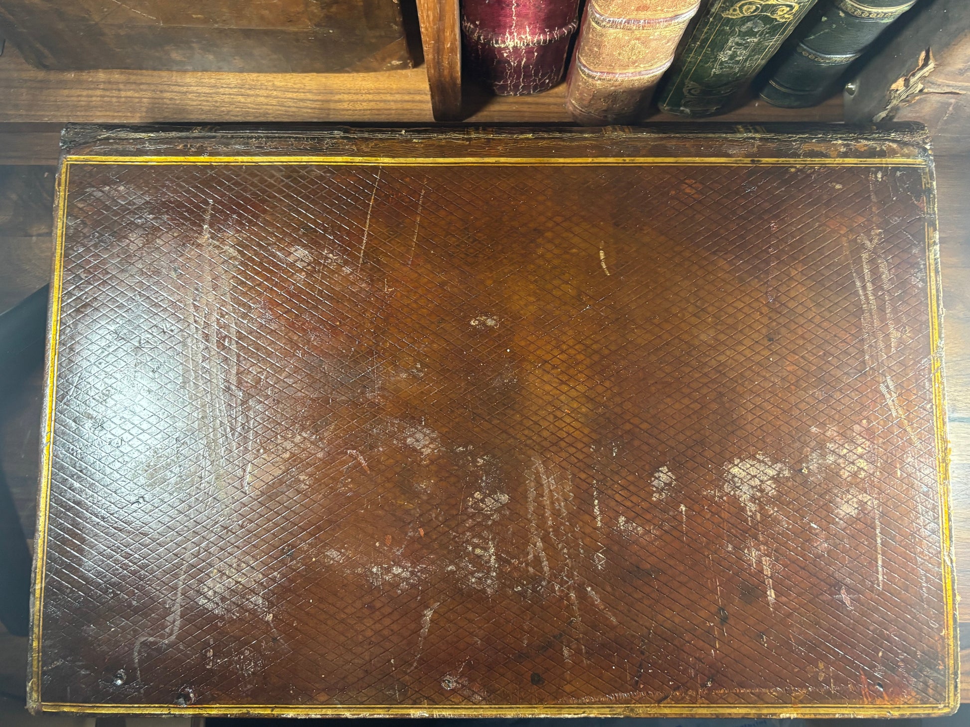 Vintage leather-bound book with wear and tear on a wooden surface